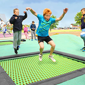 Children jumping on an outdoor playground trampoline 